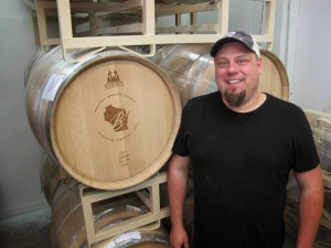 Mike Brenner, owner of Brenner Brewing in Milwaukee, stands in front of an empty beer barrel. Brenner is trying to open a craft brewery in Milwaukee by December. His application to include a tasting room is now on hold, as are his plans to file paperwork for four labels over the next few weeks. He expects to lose about $8,000 for every month his opening is delayed. (AP Photo / Carrie Antlfinger)